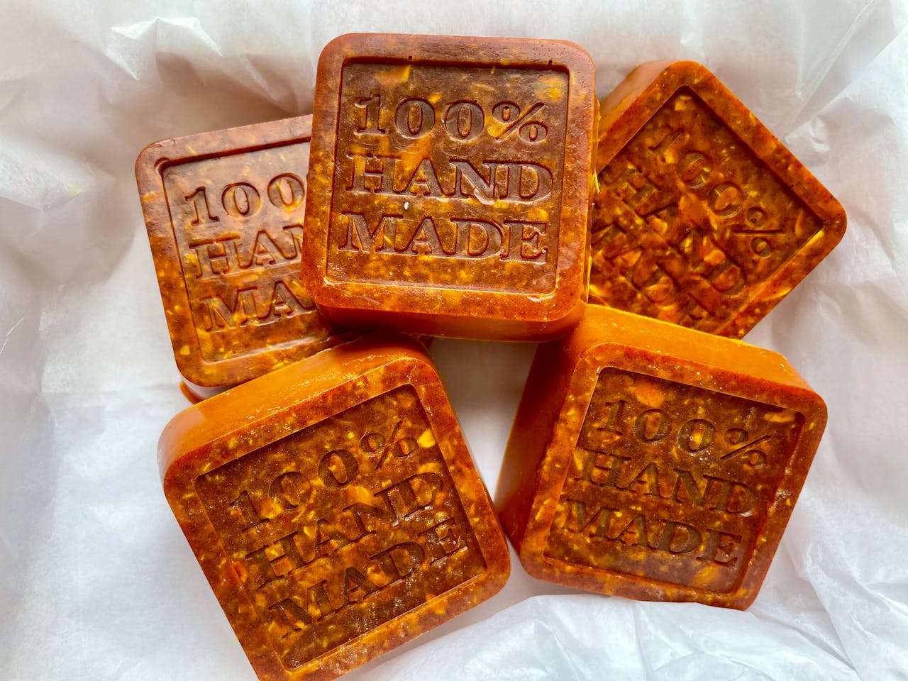 Close-up of 100% handmade artisan soaps, showcasing natural textures and warm hues.